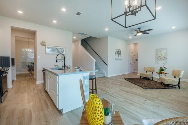 103 Periwinkle Ln, Bastrop, TX 78602 - kitchen with a chandelier, white cabinetry, a kitchen island with sink, a kitchen bar, and light wood-style flooring