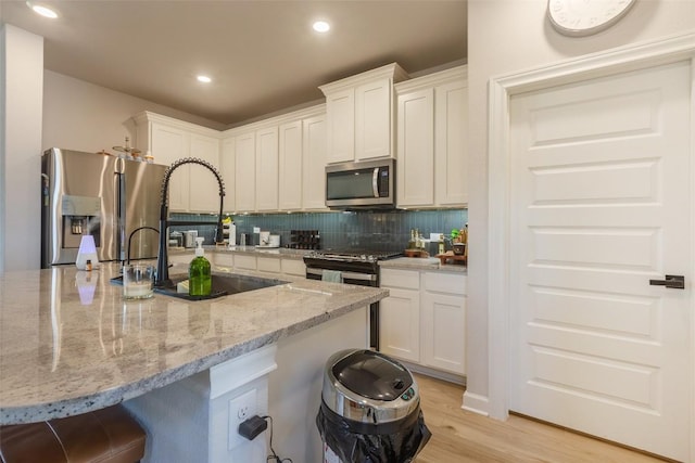 126 Periwinkle Ln, Bastrop, TX 78602 - kitchen featuring stainless steel appliances, white cabinets, a kitchen bar, and recessed lighting