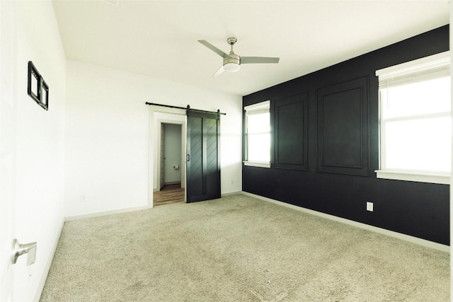 324 Millbrook Blvd, San Marcos, TX 78666 - unfurnished bedroom featuring a barn door, light carpet, and ceiling fan