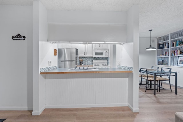 1240 Barton Hills Dr Unit 114, Austin, TX 78704 - kitchen featuring white microwave, freestanding refrigerator, stove, a textured ceiling, and wood finished floors