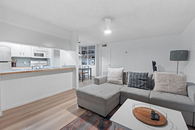 1240 Barton Hills Dr Unit 114, Austin, TX 78704 - living area with light wood finished floors, ceiling fan, and a textured ceiling