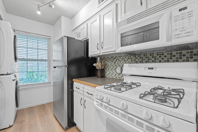 1240 Barton Hills Dr Unit 114, Austin, TX 78704 - kitchen with white appliances, stacked washer / drying machine, a textured ceiling, light wood-style flooring, and decorative backsplash