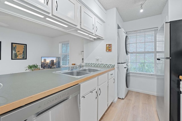 1240 Barton Hills Dr Unit 114, Austin, TX 78704 - kitchen featuring stainless steel appliances, stacked washer / dryer, light wood-style floors, white cabinetry, and a textured ceiling
