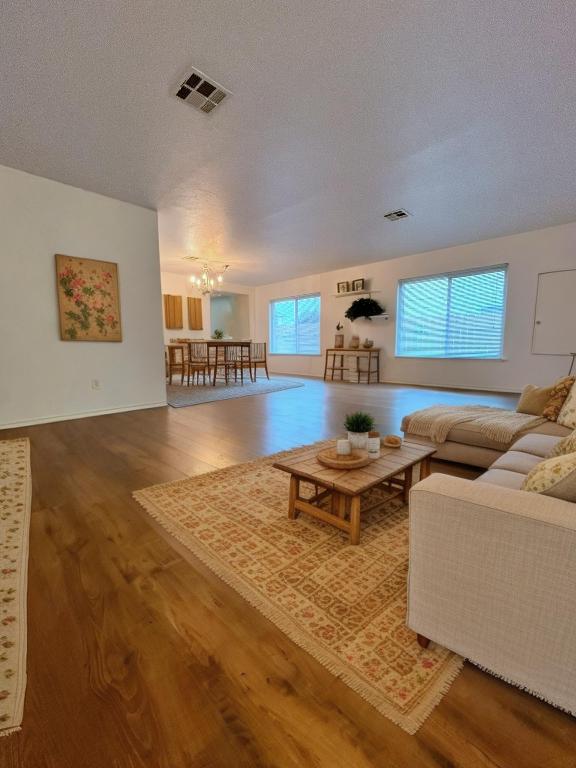 108 Bexar Forest Cv, Elgin, TX 78621 - living room with a chandelier, wood finished floors, and a textured ceiling