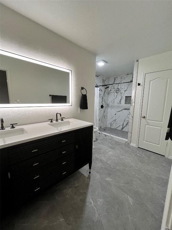 108 Bexar Forest Cv, Elgin, TX 78621 - bathroom featuring a marble finish shower, double vanity, and marble finish flooring