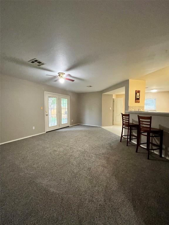 108 Bexar Forest Cv, Elgin, TX 78621 - unfurnished living room featuring a ceiling fan, carpet floors, a textured ceiling, and a dry bar