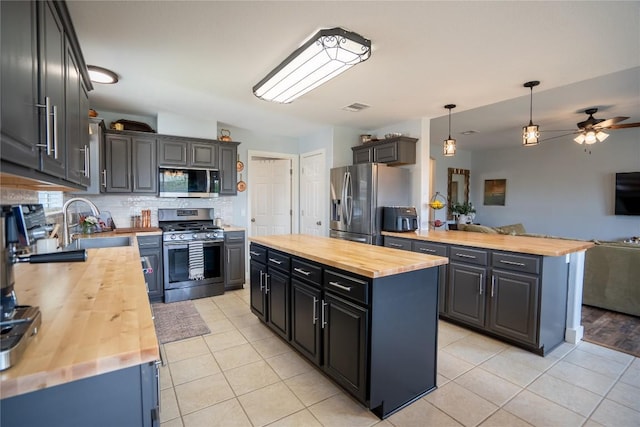 1410 Sherry Dr, Taylor, TX 76574 - kitchen featuring wood counters, appliances with stainless steel finishes, open floor plan, a center island, and light tile patterned flooring