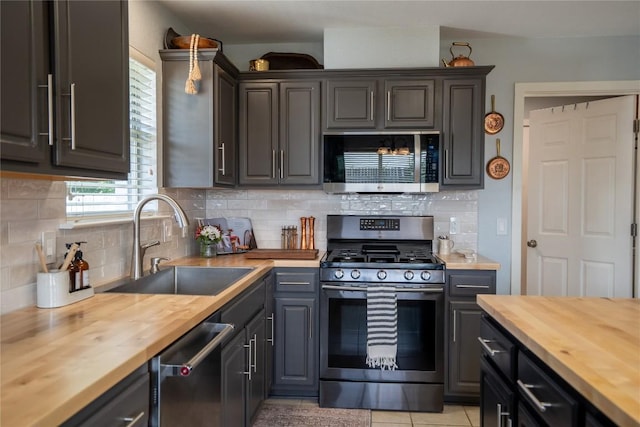 1410 Sherry Dr, Taylor, TX 76574 - kitchen featuring butcher block countertops, appliances with stainless steel finishes, tasteful backsplash, and light tile patterned floors