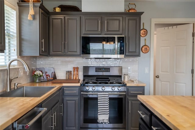 1410 Sherry Dr, Taylor, TX 76574 - kitchen with butcher block countertops, stainless steel appliances, decorative backsplash, and gray cabinets
