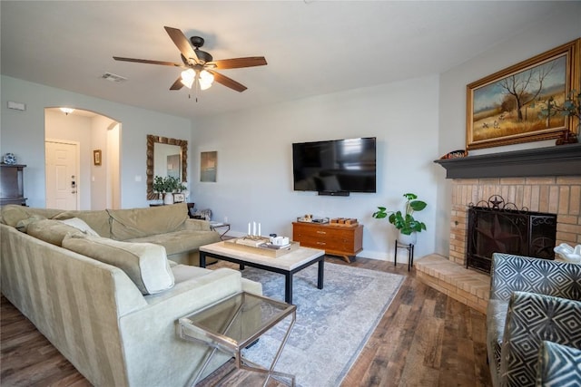 1410 Sherry Dr, Taylor, TX 76574 - living room with a ceiling fan, arched walkways, wood finished floors, and a brick fireplace