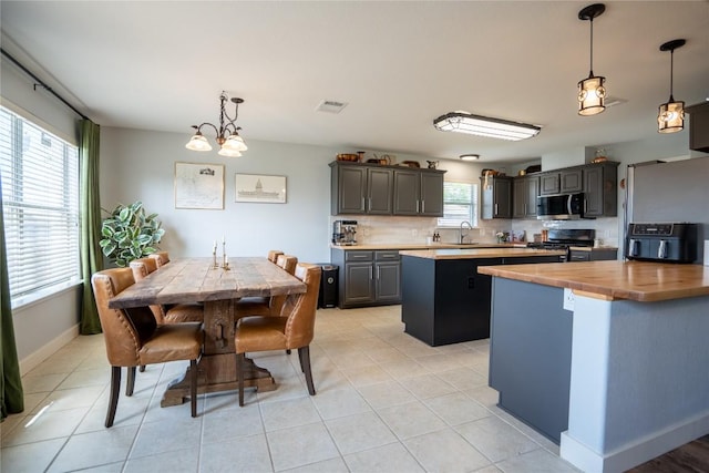 1410 Sherry Dr, Taylor, TX 76574 - kitchen with black stove, a center island, stainless steel microwave, wood counters, and tasteful backsplash