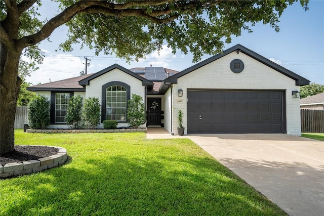 1410 Sherry Dr, Taylor, TX 76574 - ranch-style house featuring concrete driveway, roof mounted solar panels, a garage, and brick siding