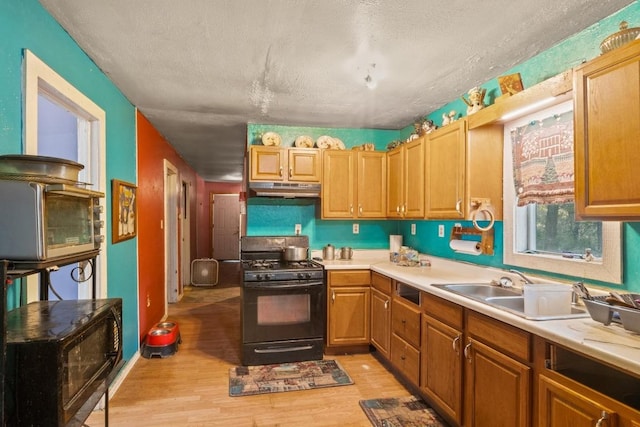 147 Sunset Hts, Bastrop, TX 78602 - kitchen featuring black gas stove, under cabinet range hood, light wood-style flooring, light countertops, and a textured ceiling