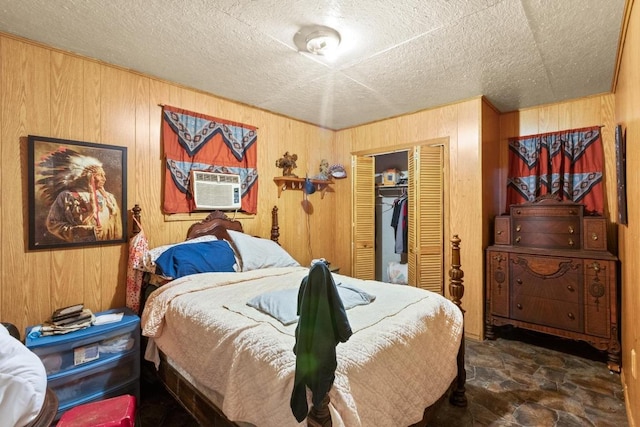 147 Sunset Hts, Bastrop, TX 78602 - bedroom with wooden walls, cooling unit, stone finish flooring, a closet, and a textured ceiling
