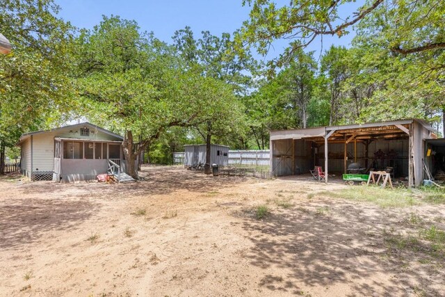 147 Sunset Hts, Bastrop, TX 78602 - view of yard featuring a sunroom, an outbuilding, a detached carport, and a pole building