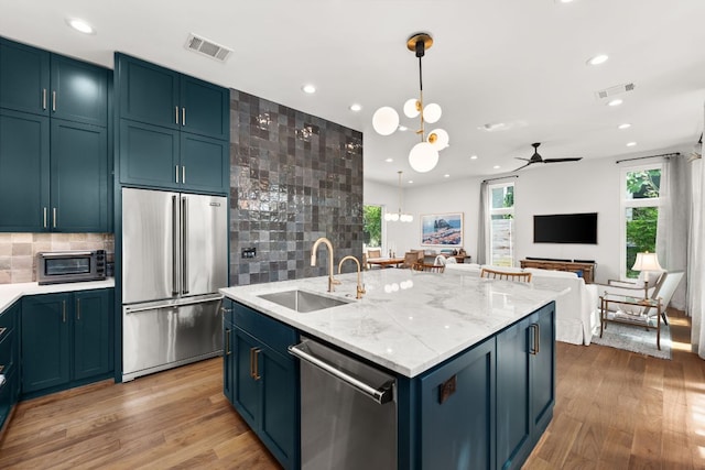 606 Augusta Ave Unit 1, Austin, TX 78703 - kitchen featuring appliances with stainless steel finishes, blue cabinetry, light wood finished floors, and recessed lighting