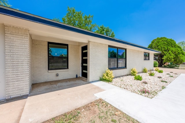 106 Heron, Highland Haven, TX 78654 - view of exterior entry with brick siding and a patio