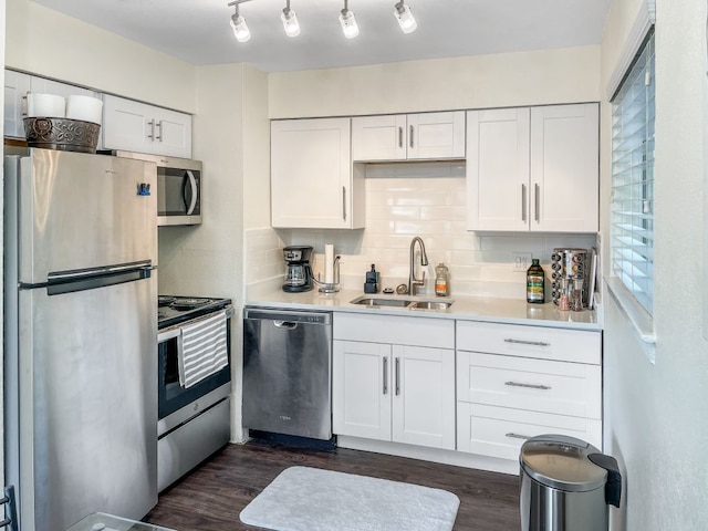 6100 Calmar Cv, Austin, TX 78721 - kitchen with appliances with stainless steel finishes, white cabinets, light countertops, dark wood finished floors, and decorative backsplash