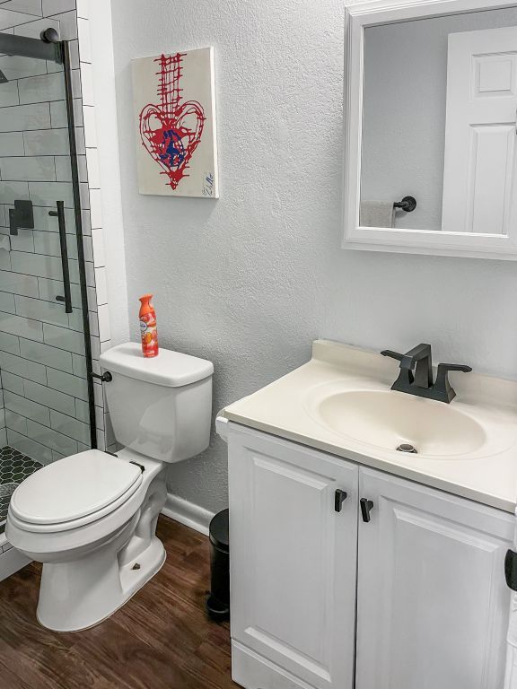 6100 Calmar Cv, Austin, TX 78721 - full bathroom with vanity, a stall shower, wood finished floors, and a textured wall