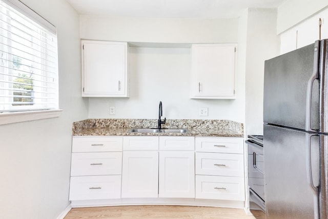 6100 Calmar Cv, Austin, TX 78721 - kitchen with freestanding refrigerator, white cabinetry, light stone counters, and range