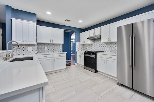 207 Presidio Dr, Leander, TX 78641 - kitchen featuring high quality fridge, range with gas cooktop, under cabinet range hood, arched walkways, and light countertops