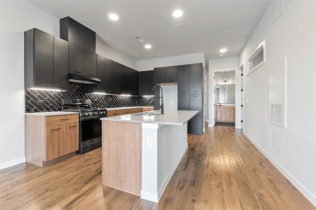 4510 Terry-O Ln Unit 415, Austin, TX 78745 - kitchen featuring gas stove, under cabinet range hood, light countertops, dark cabinets, and modern cabinets
