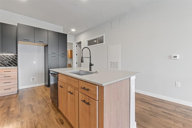 4510 Terry-O Ln Unit 415, Austin, TX 78745 - kitchen with light wood-style flooring, stainless steel dishwasher, light countertops, an island with sink, and tasteful backsplash