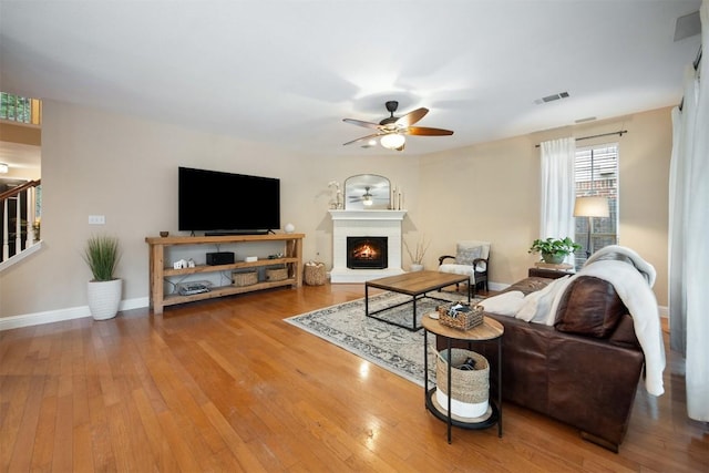 1215 Boerne Dr, Cedar Park, TX 78613 - living room featuring ceiling fan, wood-type flooring, a lit fireplace, and stairs