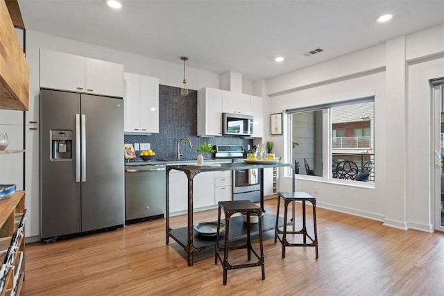 4361 S Congress Ave Unit 435, Austin, TX 78745 - kitchen featuring appliances with stainless steel finishes, white cabinetry, decorative backsplash, light wood finished floors, and recessed lighting