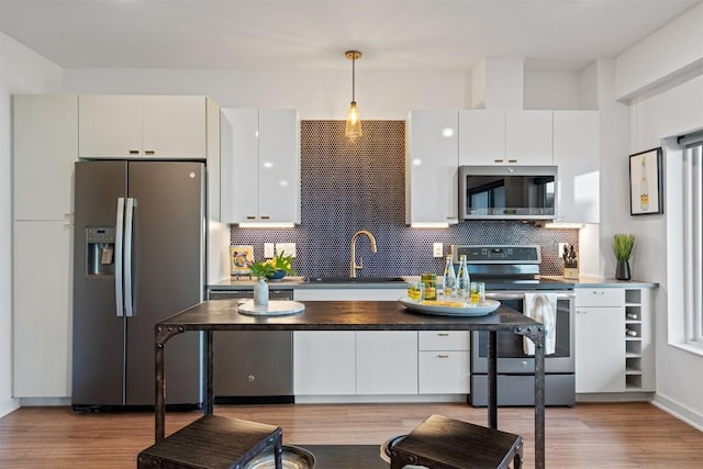 4361 S Congress Ave Unit 435, Austin, TX 78745 - kitchen featuring appliances with stainless steel finishes, decorative backsplash, light wood-style floors, pendant lighting, and white cabinets