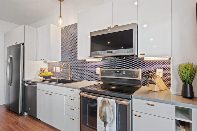 4361 S Congress Ave Unit 435, Austin, TX 78745 - kitchen with appliances with stainless steel finishes, white cabinetry, decorative backsplash, light countertops, and hanging light fixtures