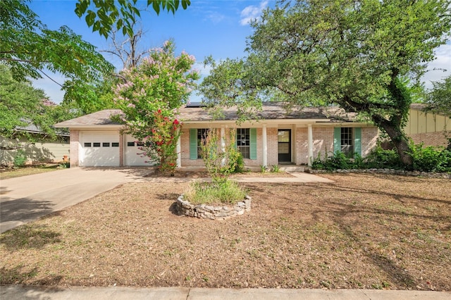 11702 Shoshone Dr, Austin, TX 78759 - ranch-style house with brick siding, a porch, an attached garage, concrete driveway, and solar panels