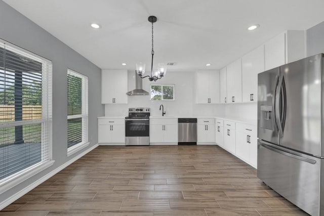 5063 Cedarside, San Marcos, TX 78666 - kitchen with appliances with stainless steel finishes, wall chimney range hood, a chandelier, dark wood-style flooring, and light countertops