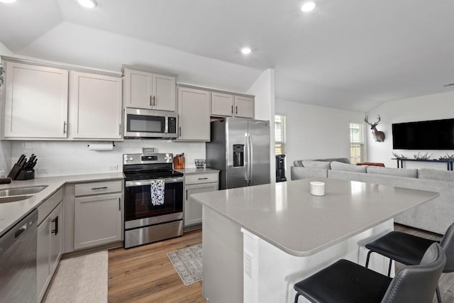 105 Perfect World Loop, Jarrell, TX 76537 - kitchen with appliances with stainless steel finishes, light wood-style floors, a kitchen breakfast bar, tasteful backsplash, and open floor plan