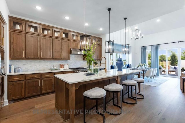1401 Snowdrop Dr, Georgetown, TX 78628 - kitchen with a chandelier, dark wood-style flooring, tasteful backsplash, an island with sink, and a breakfast bar area