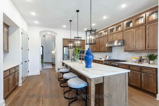 1401 Snowdrop Dr, Georgetown, TX 78628 - kitchen featuring backsplash, a kitchen bar, wood finished floors, arched walkways, and recessed lighting