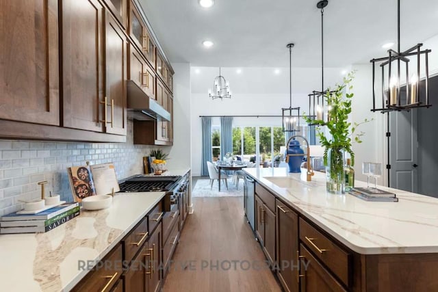 1401 Snowdrop Dr, Georgetown, TX 78628 - kitchen with dark wood-style floors, a chandelier, backsplash, a kitchen island with sink, and glass insert cabinets