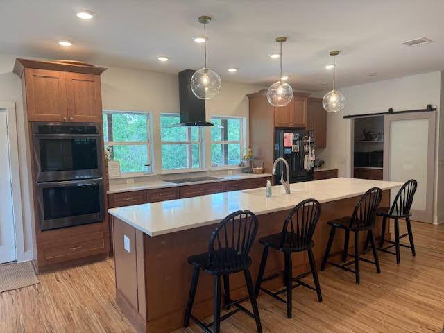 305 Goertz Dr, Red Rock, TX 78662 - kitchen with range hood, black appliances, light wood-style flooring, light countertops, and recessed lighting