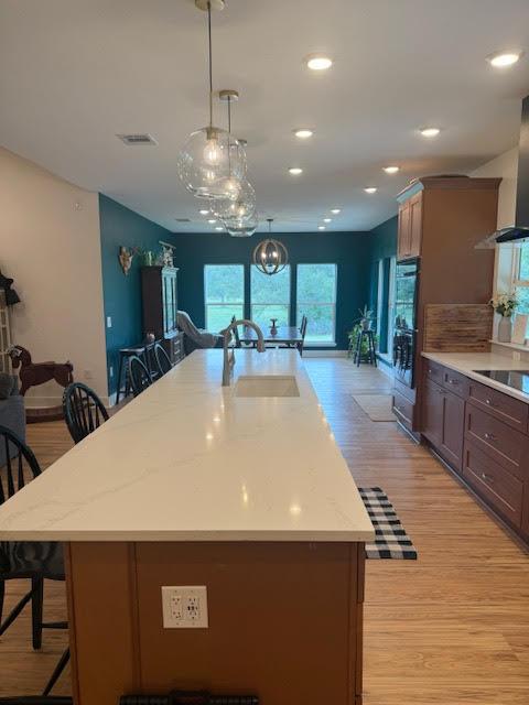 305 Goertz Dr, Red Rock, TX 78662 - kitchen with a kitchen bar, light wood finished floors, a large island, black appliances, and decorative light fixtures