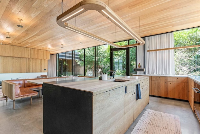 906 W 18th St, Austin, TX 78701 - kitchen featuring wood ceiling, concrete floors, light countertops, a center island, and floor to ceiling windows