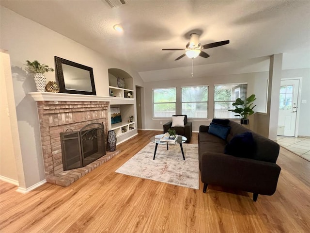612 Thrush Dr, Leander, TX 78641 - living room with built in features, ceiling fan, a brick fireplace, light wood-type flooring, and a textured ceiling