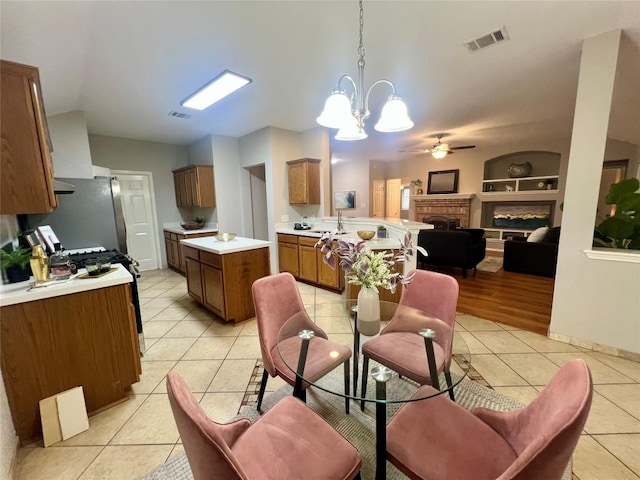 612 Thrush Dr, Leander, TX 78641 - kitchen with light tile patterned floors, brown cabinetry, freestanding refrigerator, ceiling fan, and black gas range