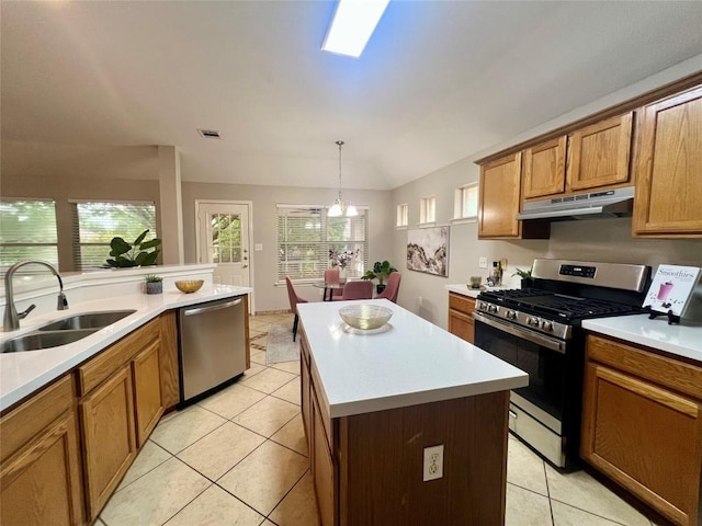 612 Thrush Dr, Leander, TX 78641 - kitchen with stainless steel appliances, under cabinet range hood, brown cabinetry, light tile patterned floors, and lofted ceiling
