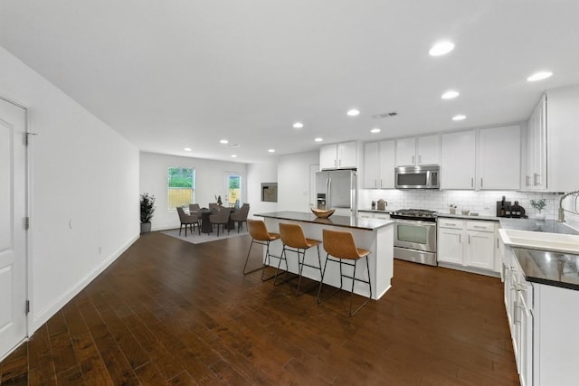 1612 Westmoor Dr, Austin, TX 78723 - kitchen featuring stainless steel appliances, dark countertops, a kitchen island, a kitchen breakfast bar, and dark wood-style floors