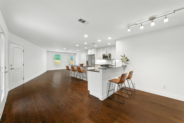 1612 Westmoor Dr, Austin, TX 78723 - kitchen featuring appliances with stainless steel finishes, a kitchen bar, recessed lighting, white cabinetry, and dark wood-style flooring