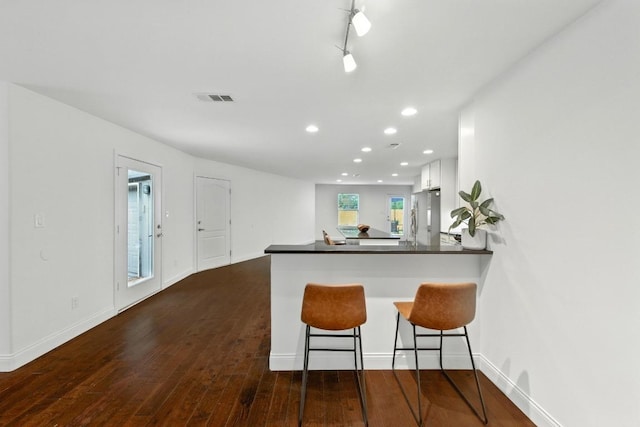 1612 Westmoor Dr, Austin, TX 78723 - kitchen featuring freestanding refrigerator, a peninsula, white cabinetry, recessed lighting, and dark wood-type flooring