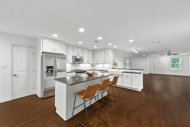 1612 Westmoor Dr, Austin, TX 78723 - kitchen featuring appliances with stainless steel finishes, a peninsula, dark wood finished floors, white cabinetry, and recessed lighting