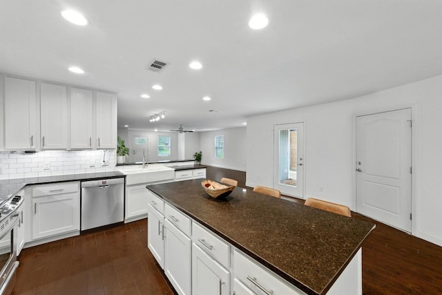 1612 Westmoor Dr, Austin, TX 78723 - kitchen with appliances with stainless steel finishes, recessed lighting, dark wood finished floors, a peninsula, and white cabinets