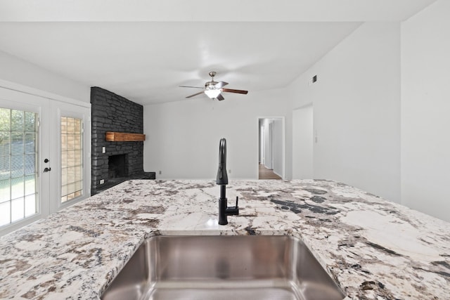 10001 Woodglen Dr, Austin, TX 78753 - kitchen featuring light stone countertops, a ceiling fan, a stone fireplace, and open floor plan