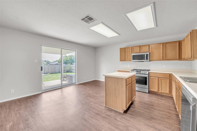 100 Grant Cv, Hutto, TX 78634 - kitchen with appliances with stainless steel finishes, light wood-type flooring, a kitchen island, light countertops, and a textured ceiling